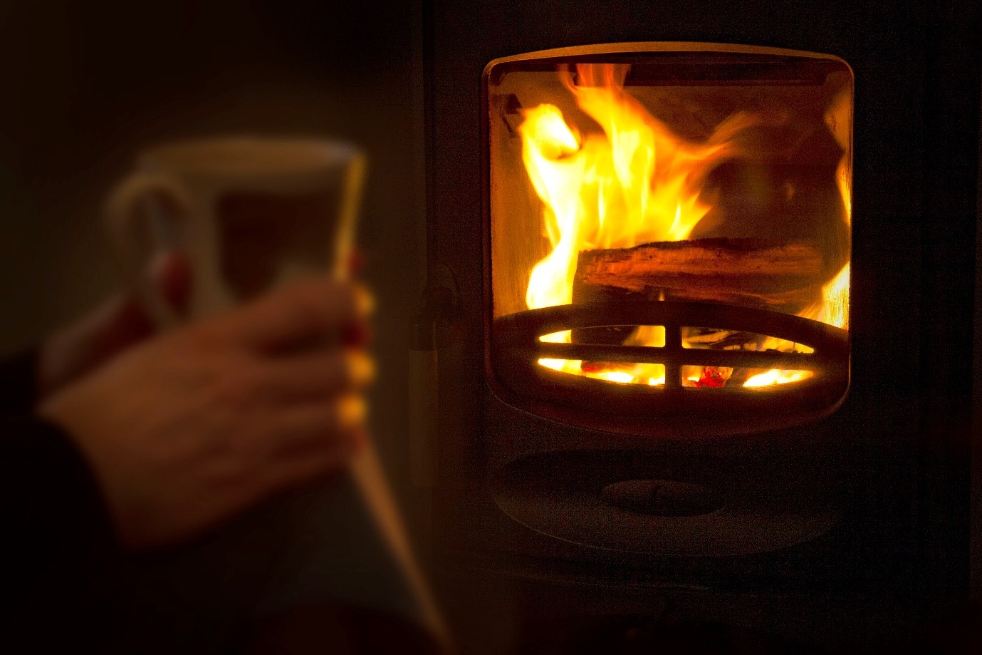 Image of a person sat in front of a wood burning stove