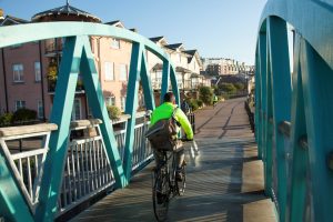 Man cycling along Bristol harbourside in a high visibility jacket.