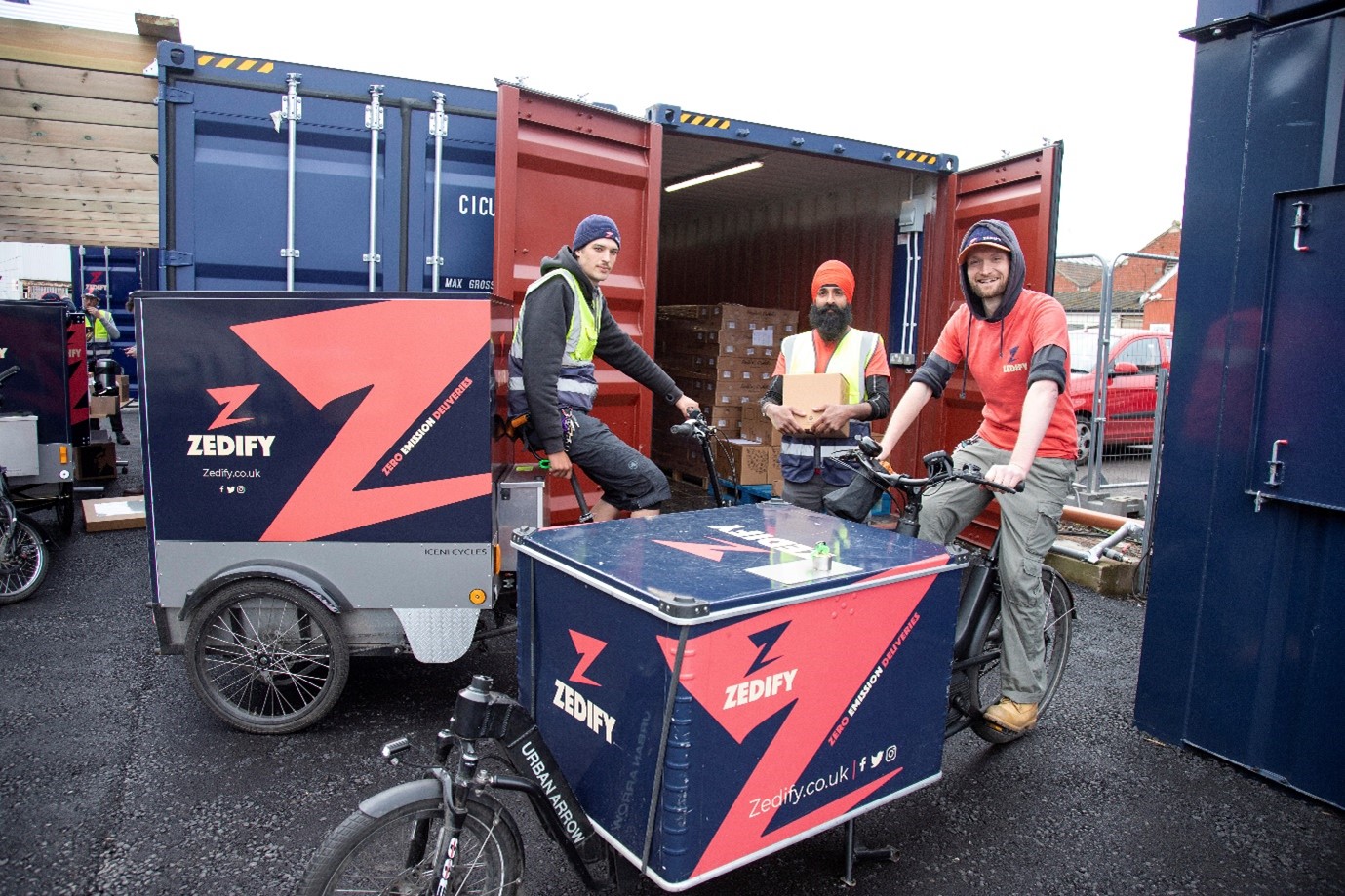 Three men stood around Zedify branded delivery bikes.